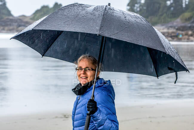 Donna che cammina sotto la pioggia, Tofino, British Columbia, Canada — Foto stock