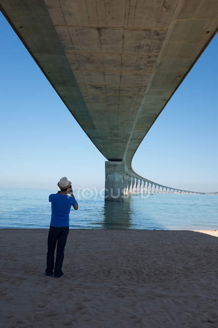 Hombre fotografiando ile de re bridge, La Rochelle, Francia - foto de stock