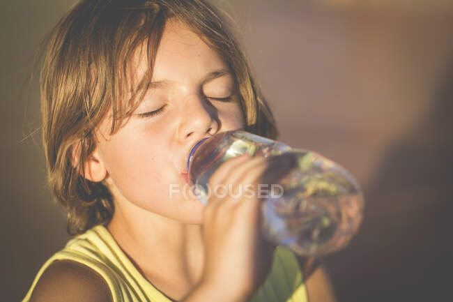 Хлопчик п'є пляшку води на природі — стокове фото