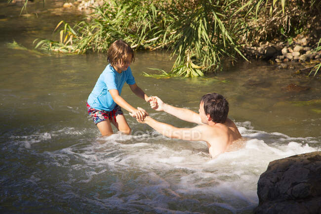 Padre e hijo jugando en un río - foto de stock