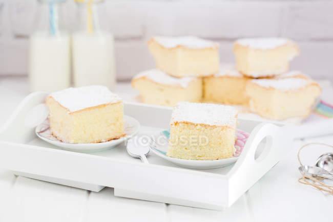 Tranches de gâteau éponge et bouteilles de lait — Photo de stock