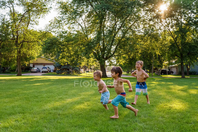 Three boys running in garden — Stock Photo