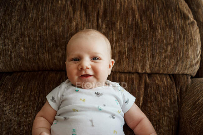 Smiling baby boy sitting in an armchair — Stock Photo