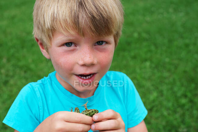 Portrait of a boy holding frog on nature — Stock Photo