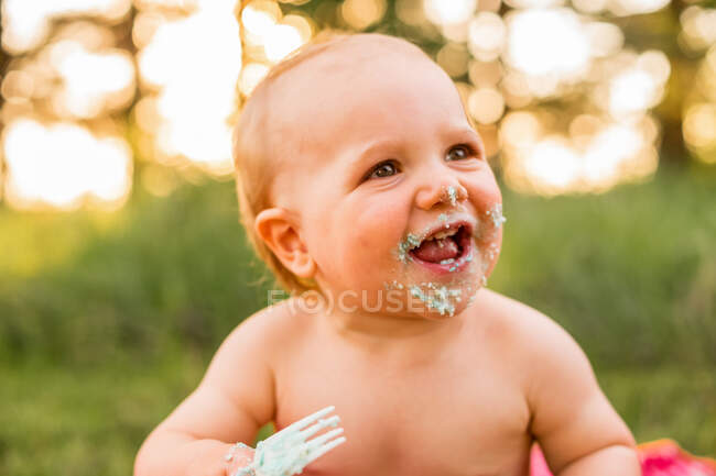 Portrait of a smiling baby boy with cake on his face — Stock Photo
