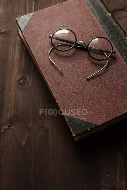 Spectacles on a book on wooden table — Stock Photo