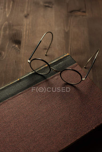 Vista de primer plano de gafas en un libro sobre mesa de madera - foto de stock
