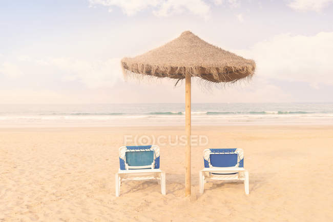 Blick auf zwei Liegestühle und einen Sonnenschirm am Strand — Stockfoto