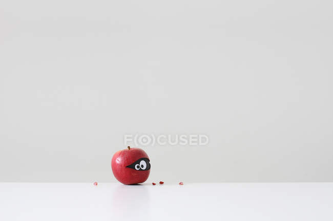 Red apple with eyes hiding inside over white background — Stock Photo