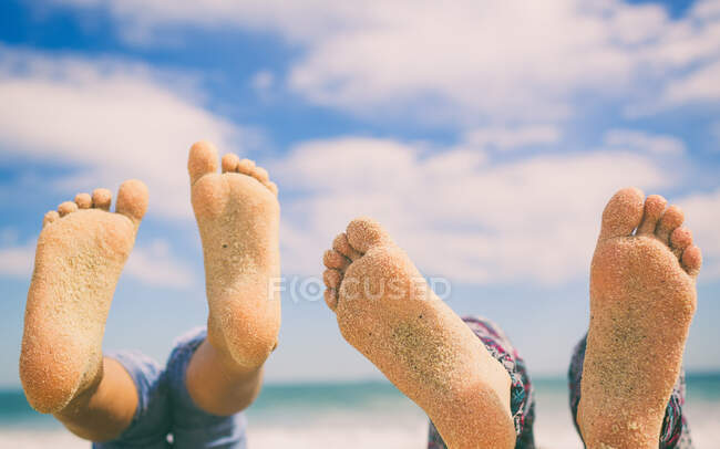 Крупный план двух пар футов на пляже, покрытых песком — стоковое фото