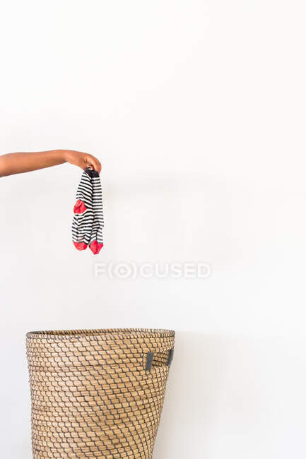 Mão colocando meias sujas na cesta de roupa — Fotografia de Stock