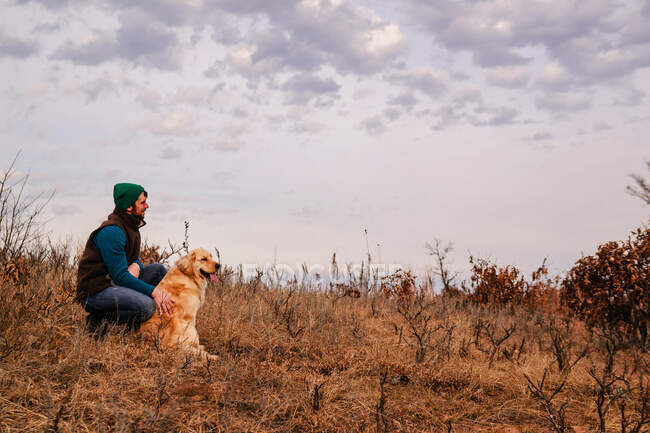 Чоловік сидить з собакою в сільському пейзажі — стокове фото