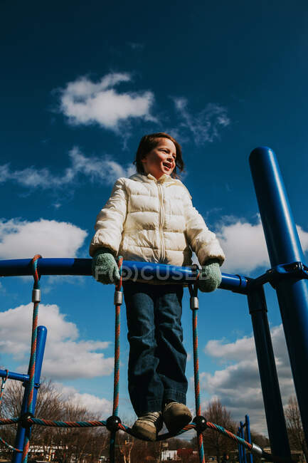 Menina de pé no quadro de escalada no parque infantil — Fotografia de Stock