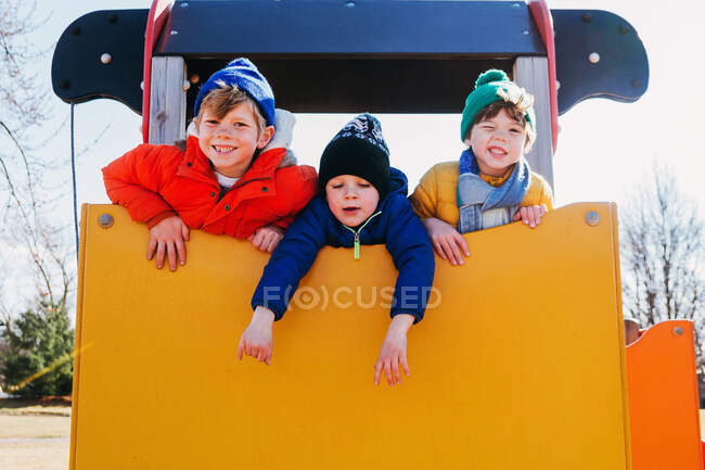 Tres chicos jugando en un parque infantil - foto de stock