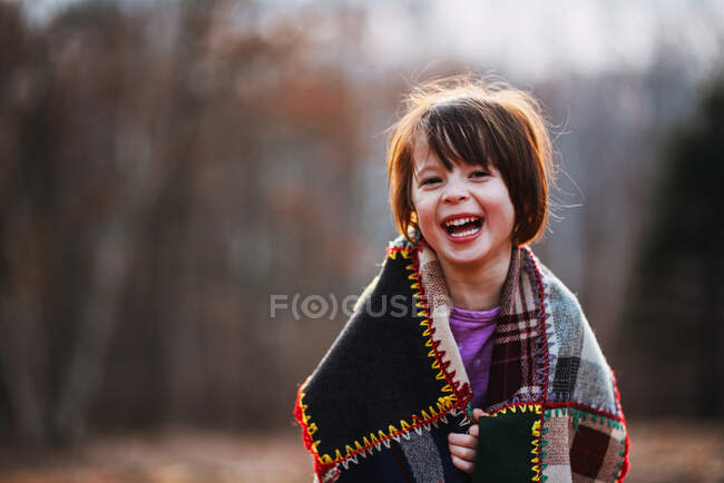 Portrait d'une fille enveloppée dans une couverture riant — Photo de stock