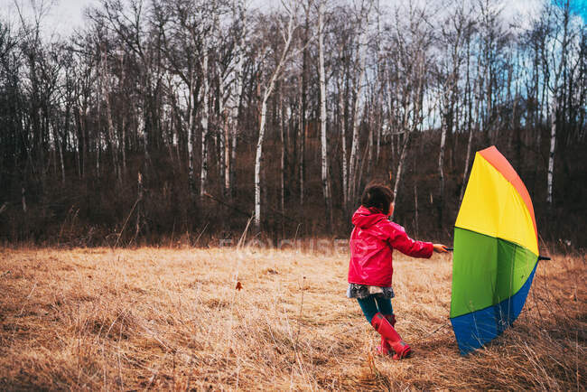 Menina segurando um guarda-chuva multi-colorido — Fotografia de Stock