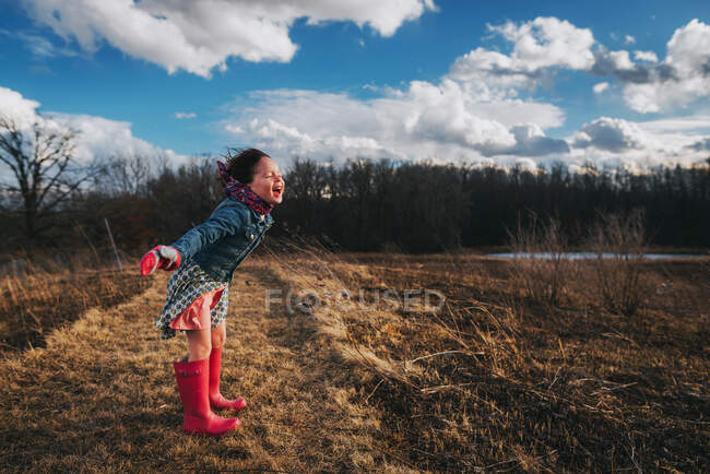 Дівчина з простягнутими руками кричить у вітер — стокове фото