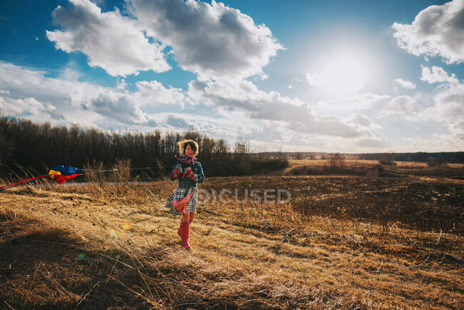 Fille debout sur une colline tenant un cerf-volant sur la nature — Photo de stock