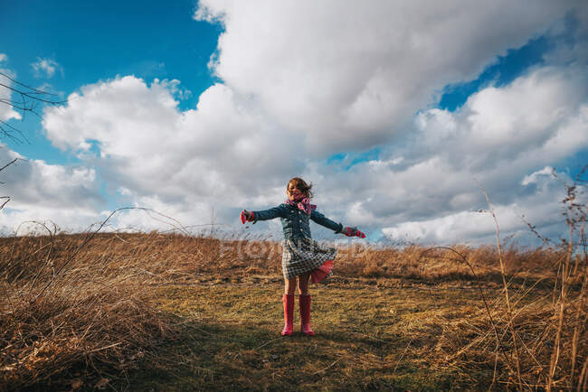 Girl standing with outstretched arms in the wind — Stock Photo
