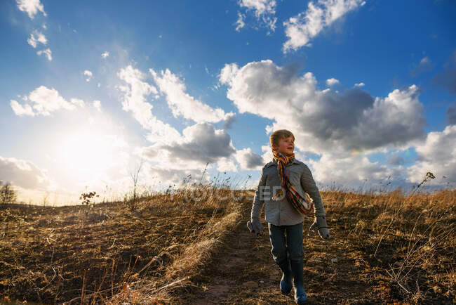 Niño caminando por una colina en un día ventoso - foto de stock