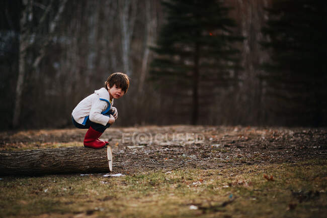 Boy crouching on a log getting ready to jump — Stock Photo