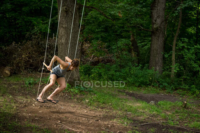 Femme sur une balançoire en forêt — Photo de stock