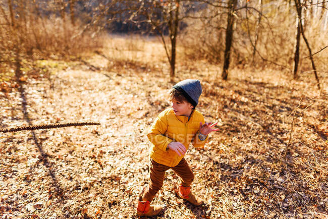 Ragazzo che gioca con un bastone nella foresta — Foto stock
