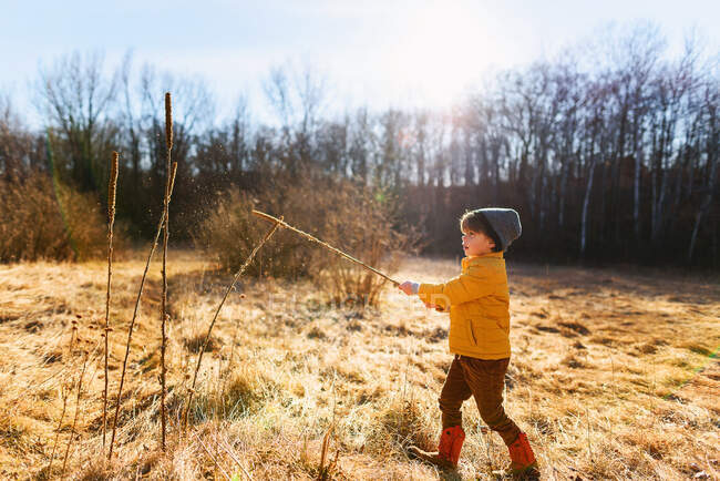 Menino brincando com um pau na floresta — Fotografia de Stock