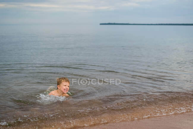 Adorable petit garçon nageant dans le lac — Photo de stock