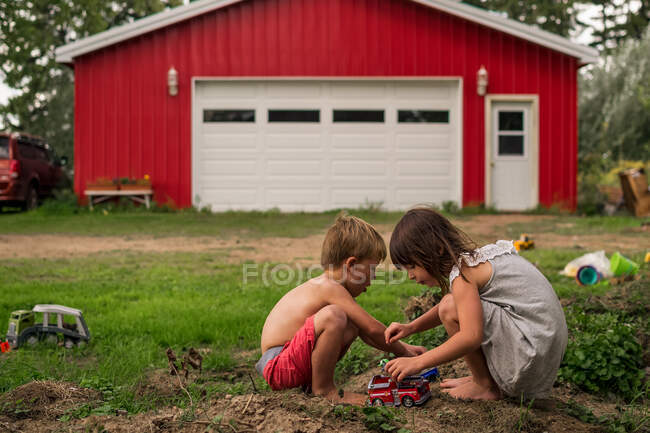 Niño y niña jugando con coches de juguete - foto de stock