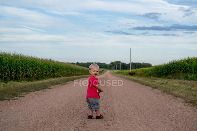 Ragazzo a piedi lungo la strada di campagna — Foto stock