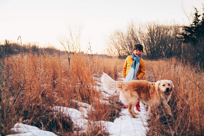 Boy walking through rural landscape with golden retriever dog — Stock Photo