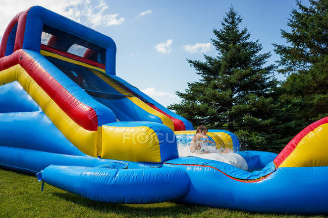 Boy playing on inflatable water slide — Stock Photo