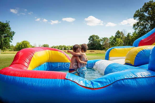 Two boys hugging on an inflatable water slide — Stock Photo