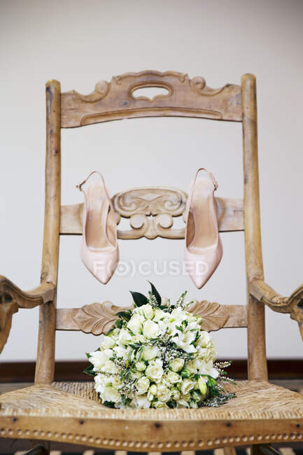 Bouquet de mariage et chaussures de mariée sur une chaise — Photo de stock