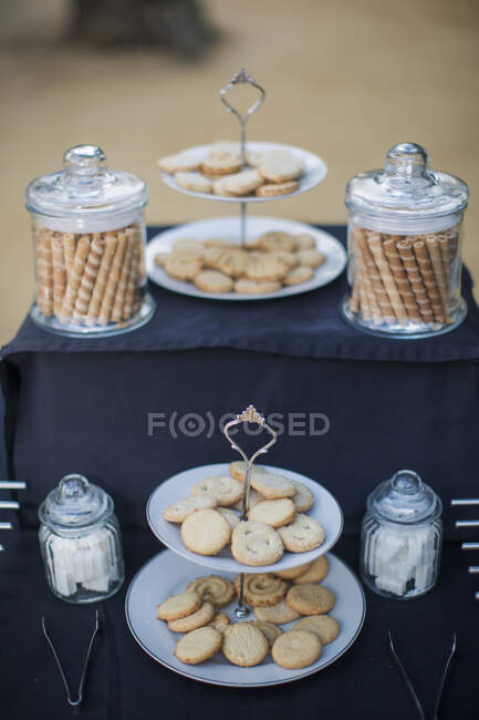 Two tier cake stands and jars filled with cookies — Stock Photo