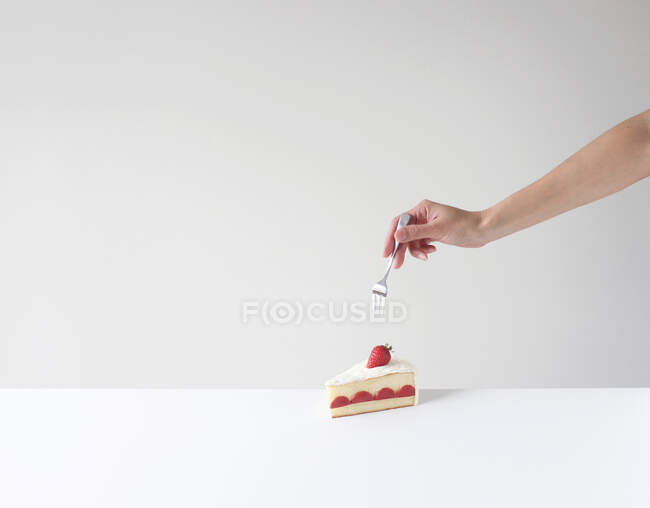 Mão segurando um garfo prestes a comer uma fatia de bolo — Fotografia de Stock