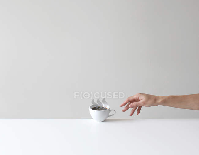 Mano que busca una taza conceptual de café - foto de stock