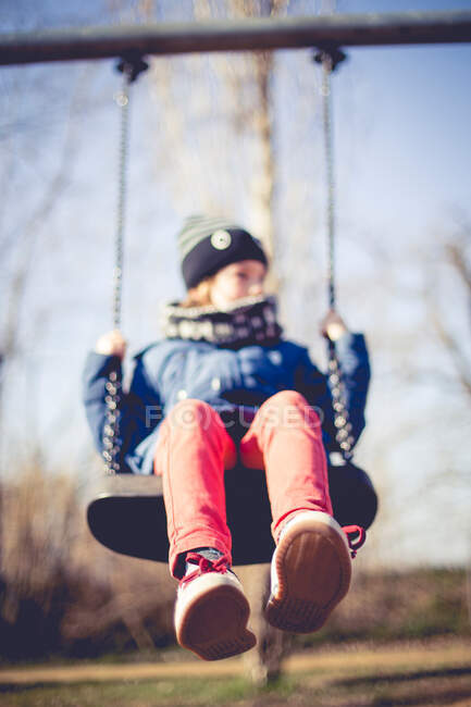 Garçon assis sur une balançoire dans le parc — Photo de stock