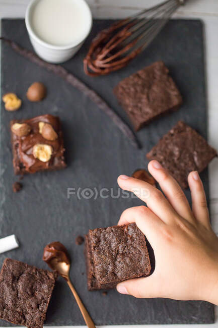 Рука хлопця тягнеться до шоколадного брауні. — стокове фото