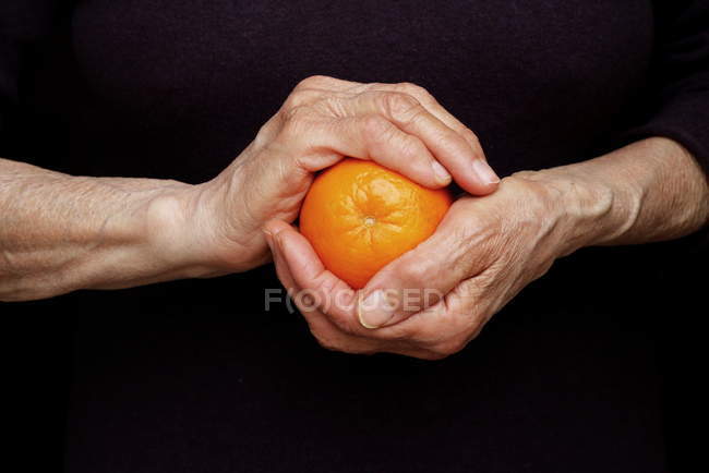 Руки женщины держат апельсин, вид крупным планом — стоковое фото