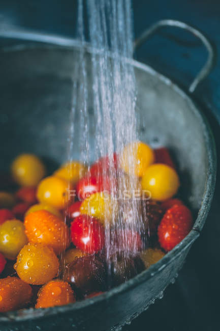 Tomates de cereja em um escorredor abaixo da água corrente — Fotografia de Stock