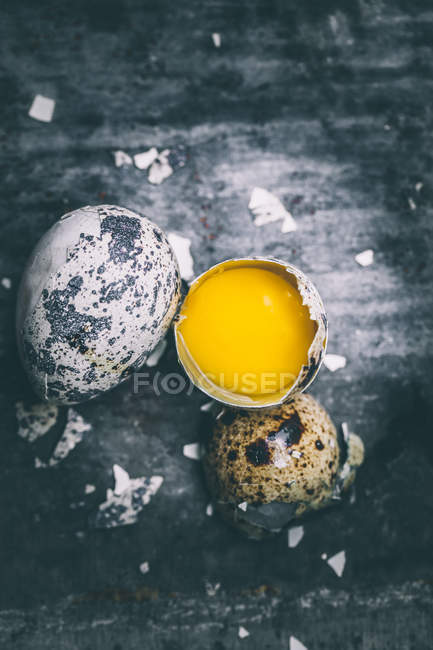 Перепелиное яйцо, скорлупа и желток над деревенским столом — стоковое фото