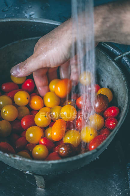 Homem mão lavando tomates cereja em escorredor, vista close-up — Fotografia de Stock