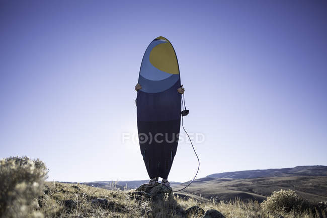 Man holding a surfboard in the desert, Wyoming, America, USA — Stock Photo