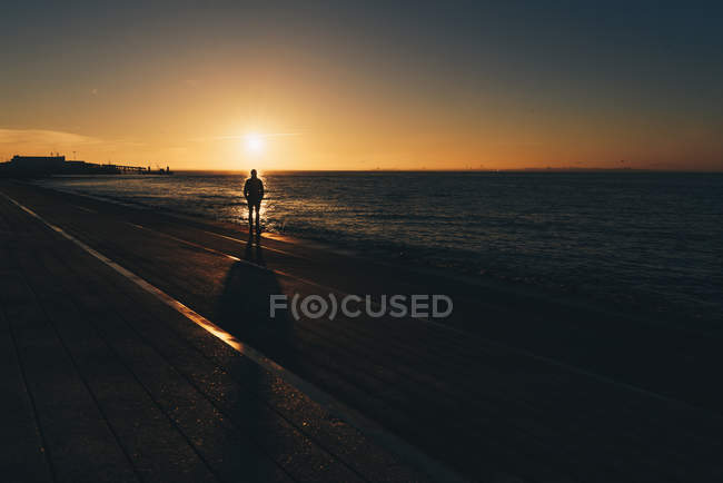 Силует чоловіка, що стоїть на пляжі на заході сонця (Лісабон, Португалія). — стокове фото