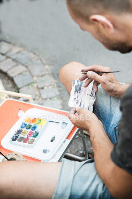 Man sitting in street painting picture — Stock Photo