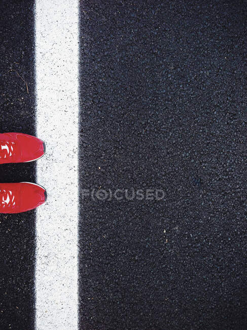 Человек в красных кроссовках стоит на дороге — стоковое фото