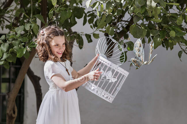 Menina liberando uma borboleta de sua gaiola — Fotografia de Stock