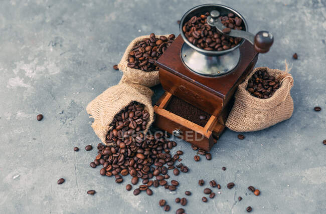 Molinillo de café con sacos de granos de café - foto de stock
